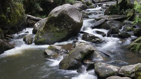 Rocky Stream Flowing Between Large Mossy Rocks Foto stock