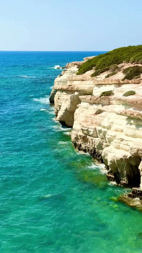 Rocky white cliffs next to bright blue ocean water Stock Footage 334593247