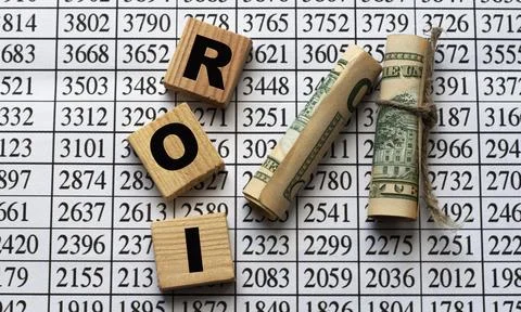 ROI - acronym on cubes on paper background with numbers and banknotes Stock Photos