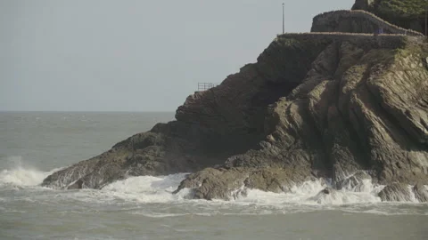 Roiled sea waves crashing on rocky cliff in North Devon Stock Footage 136883553