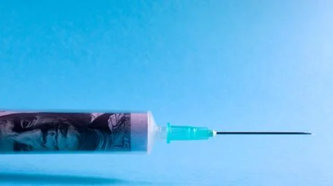 A roll of 100 dollars money inserted into a white medical hypodermic needle o Stock Photos