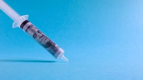 A roll of 100 dollars money inserted into a white medical hypodermic needle.. Stock Photos