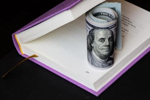 Roll of 100 dollars in violet book Stock Photos