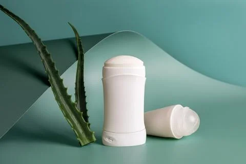 Roll on antiperspirant and solid deodorant near fresh aloe leaves. Stock Photos