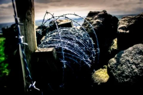 Roll of barbwire on a dry stone wall rural scene stock photo Stock Photos