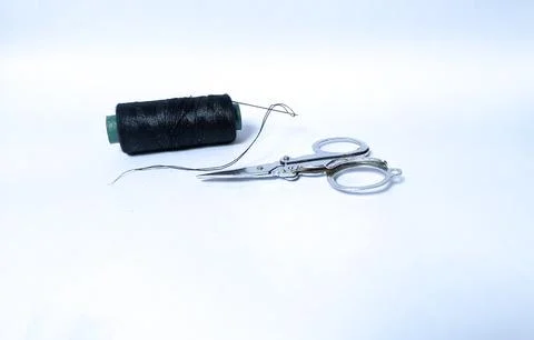 A roll of black threads and a small scissors Stock Photos