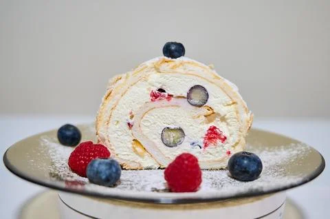 Roll cake with cream, raspberry and blueberries Stock Photos