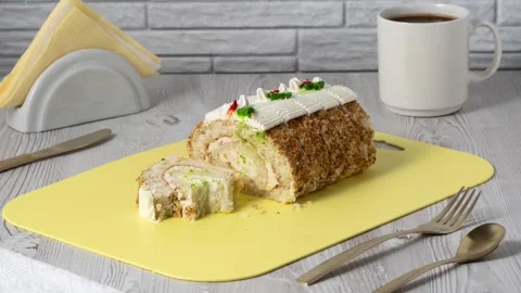 A roll cake sits on a yellow tray next to a white coffee cup Stock Footage 335463423