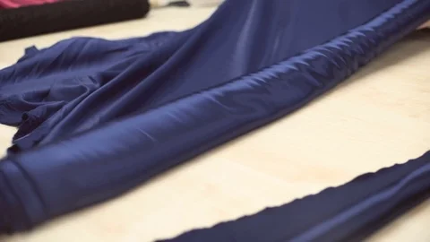 Roll of dark blue silk material unfolding on special table Stock Footage 73286642