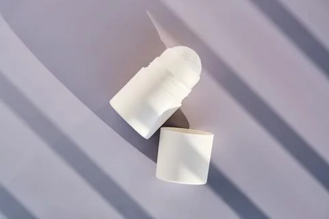 Roll-on deodorant on a purple background with shadow stripes. Stock Photos