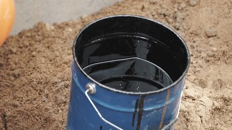 Roll dipping in blue bucket with black tar or paint on sand surface Video stock 72631179