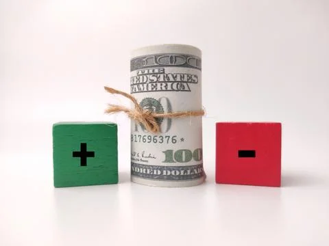A roll of dollar bills sits between a green block with a plus sign and a re.. 库存照片