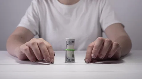 A roll of dollar bills stands on a white table in close-up. Stock Footage 276645408