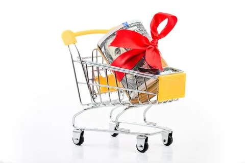 Roll of dollars bill banknotes with red ribbon in supermarket trolley cart co Foto stock