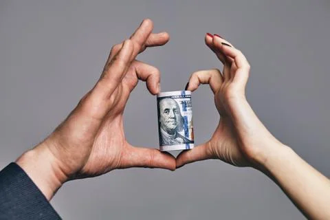 A Roll of dollars with the heart made of two hands. love money concept Stock Photos