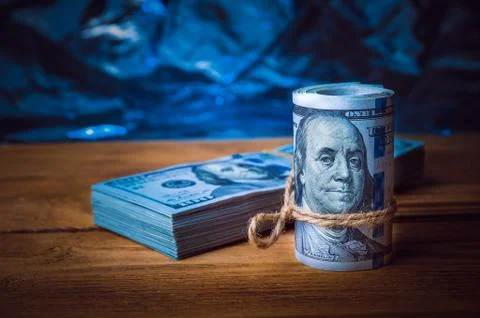 A roll of dollars with a pack of dollars on the background of textured wooden Stock Photos
