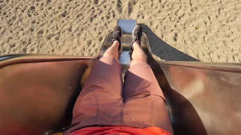 Roll down on chrome steel slider on playground. Legs with running shoes make mov Stock Footage