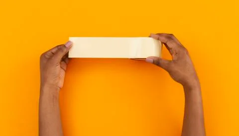 Roll of duct tape in female hands over orange background Stock Photos