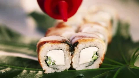 Roll with eel, cheese and cucumber on a tropical leaf watered unagi sauce Stock Footage 62191780