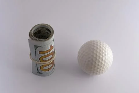 A roll of one hundred US dollar bills tied with a rubber band next to the gol Stock Photos