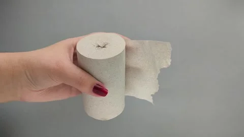 A roll of paper paper in a womans hand on a gray background. Recycled Pulp Stock Footage 324554608