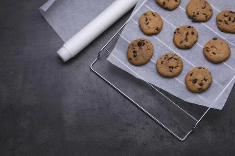 Roll of parchment baking paper and cooling rack with tasty cookies on dark .. Stock Photos