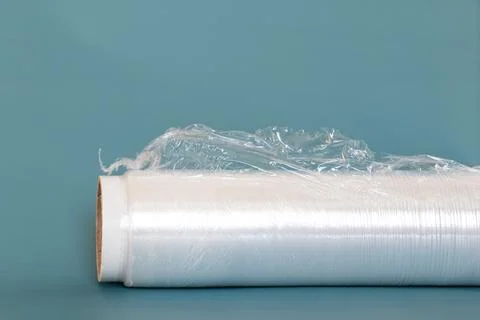 A roll of plastic wrap with a torn edge lies on a blue background Stock Photos
