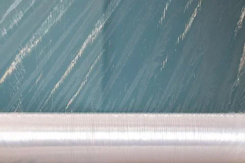 A roll of plastic wrap with a torn edge lies on a blue background Stock Photos