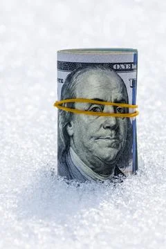 Roll of us dollar banknotes on the snow surface Stock Photos