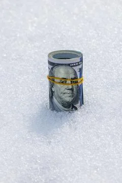 Roll of us dollar banknotes on the snow surface 库存照片