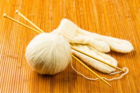 Roll of white soft knitting yarn and knitting mittens Stock Photos