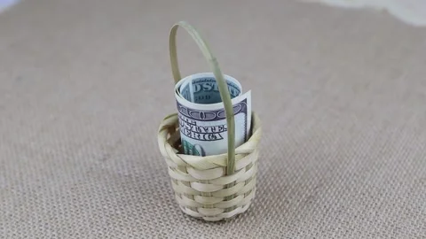Rolled 100 dollar banknotes placed in a small basket rotate on a round table Vidéo 143084238