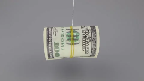 Rolled up 100 dollar banknotes rotate on a thread on a gray background, close up Vídeo Stock 141927039