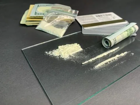 Rolled 100 us dollars, 2 lines of cocaine, plastic bag with illegal drugs and Stock Photos