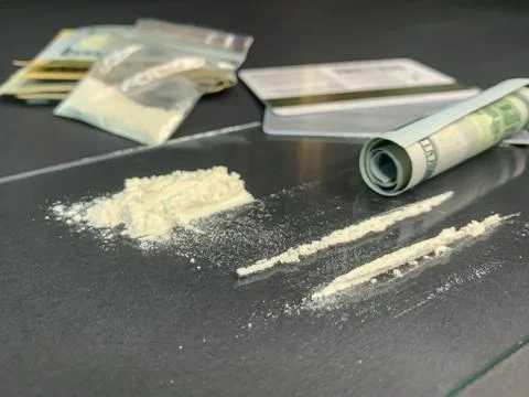 Rolled 100 us dollars, 2 lines of cocaine, plastic bag with illegal drugs and Stock Photos