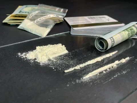 Rolled 100 us dollars, 2 lines of cocaine, plastic bag with illegal drugs and Stock Photos