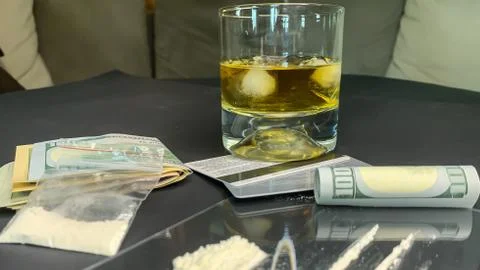 Rolled 100 us dollars, 2 lines of cocaine, a glass of whiskey, plastic bag wi Stock Photos