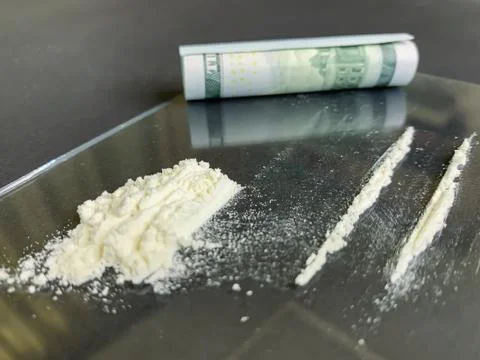 Rolled 100 us dollars and 2 lines of cocaine  on a gray background. Illegal d Stock Photos