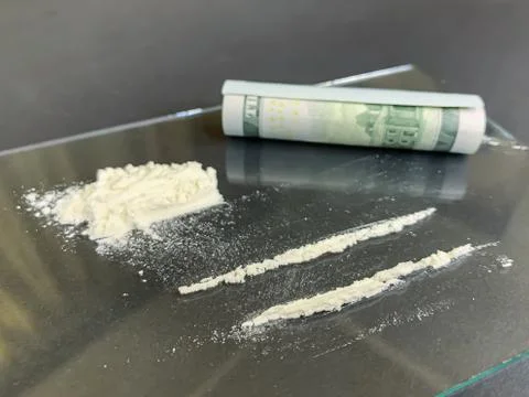 Rolled 100 us dollars and 2 lines of cocaine  on a gray background. Illegal d Stock Photos