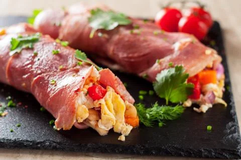 Rolled bacon stuffed with scrambled eggs and vegetables Stock Photos