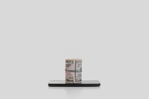 The rolled up banknotes are on the smartphone. The concept of selling goods t Stock Photos