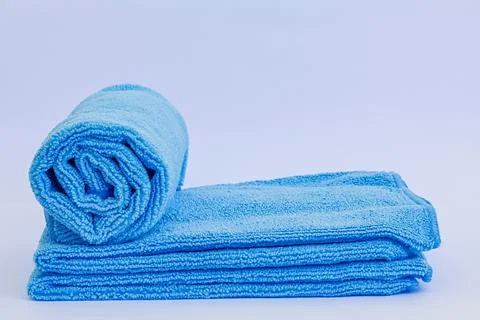 Rolled blue microfiber towel with low pile height on stack of towel isolate.. 스톡 사진