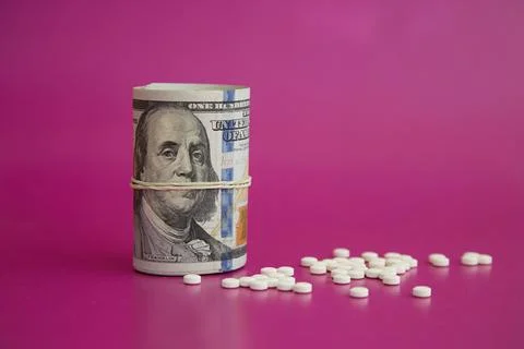 Rolled bundle of hundred-dollar bills with a rubber band covering Franklin's  Stock Photos