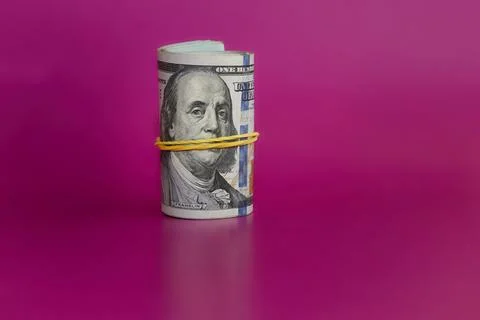 Rolled bundle of hundred-dollar bills on a pink background, hundred-dollar bi Stock Photos