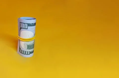 Rolled bundle of one hundred dollar bills  isolated on yellow background Stock Photos