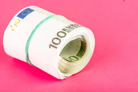 Rolled bundle of one hundred euro banknotes tied with a rubber band. Stock Photos