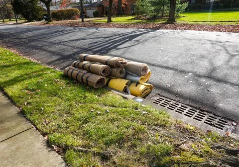 Rolled up carpet and under padding in a street by a curb  Stock Photos