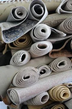 Rolled carpet samples stacked in storage with neutral tones, woven textures Stock Photos