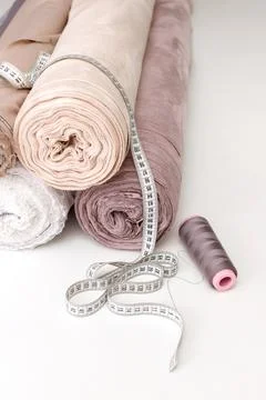 Rolled-up cloth, centimeter and thread on the white table at the seamstress Foto stock