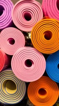 Rolled colorful yoga and exercise mats arranged in a vibrant spiral pattern. Stockfoto's